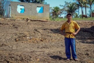 A farmer poses in front of burnt land