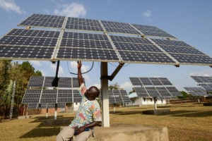 A man looks up at a solar panel in a solar farm in Arua, Uganda.