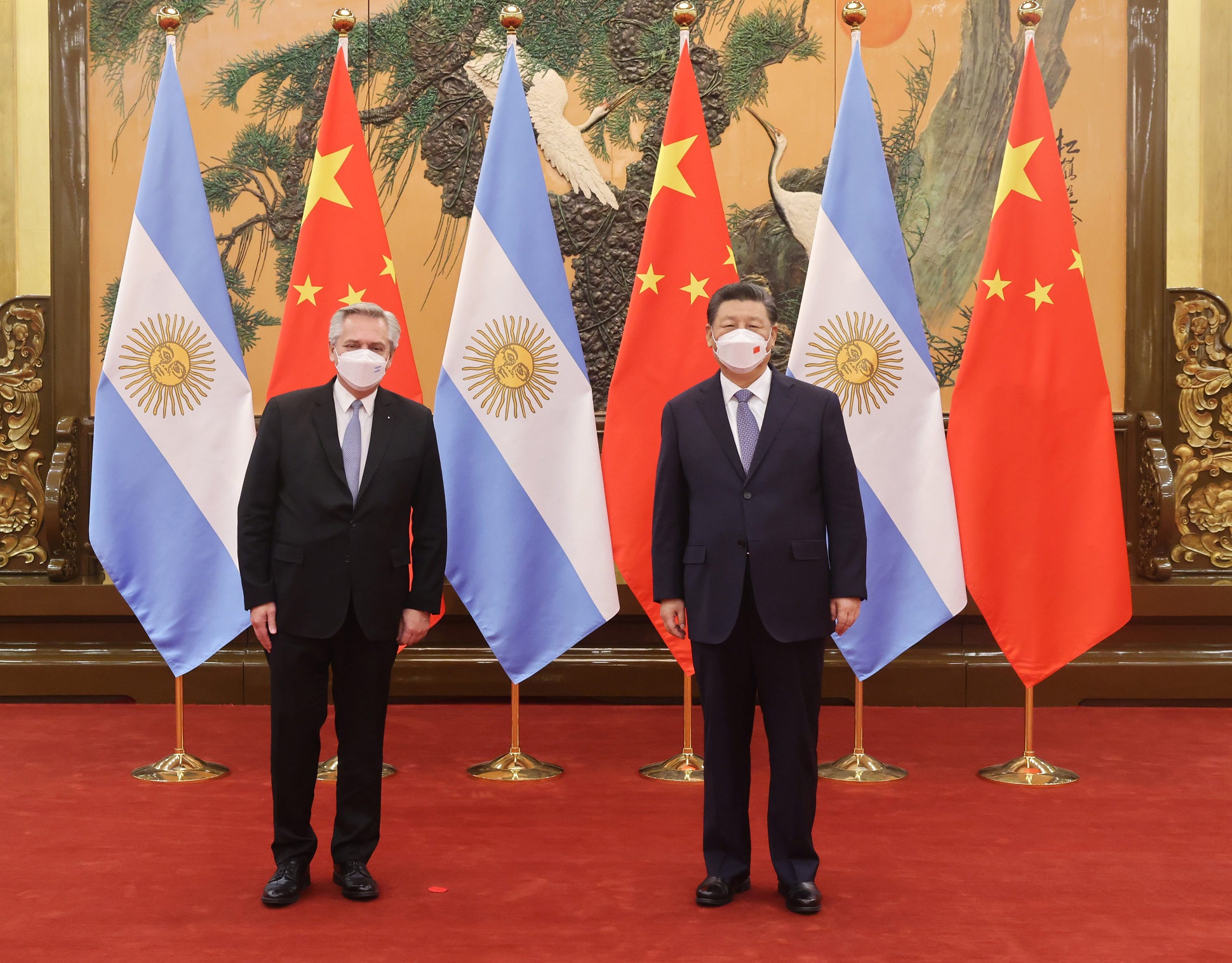 alberto fernandez and xi jinping pose with chinstraps on and flags of China and Argentina behind.