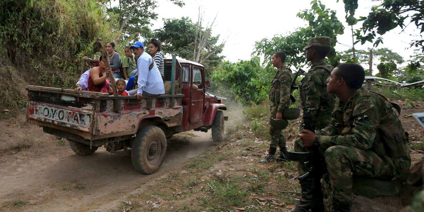 People in a pick-up truck and military on the road