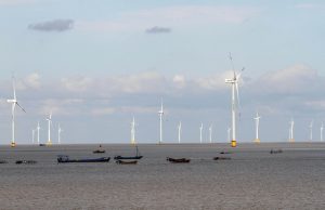 <p>Fishing boats pass a wind farm in Jiangsu province. China is exploring the potential of turning wind turbine bases into “marine ranches”, where seafood can be harvested for human consumption. (Image: Alamy)</p>