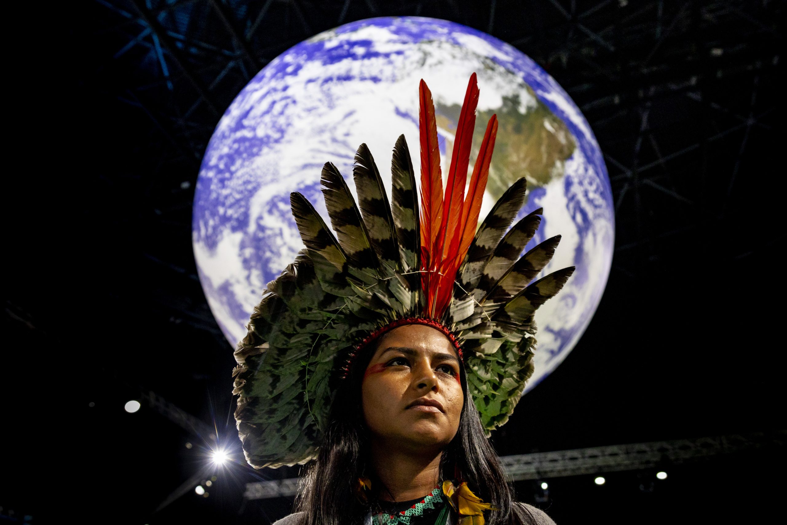Indigenous leader Juma Xipaia poses in front of an illustration of the Earth.