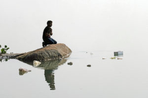 Man kneeling on a rock near reflective river