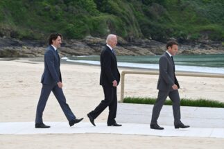 El presidente estadounidense Joe Biden camina por una playa con su par canadiense Justin Trudeau y el francés Emmanuel Macron
