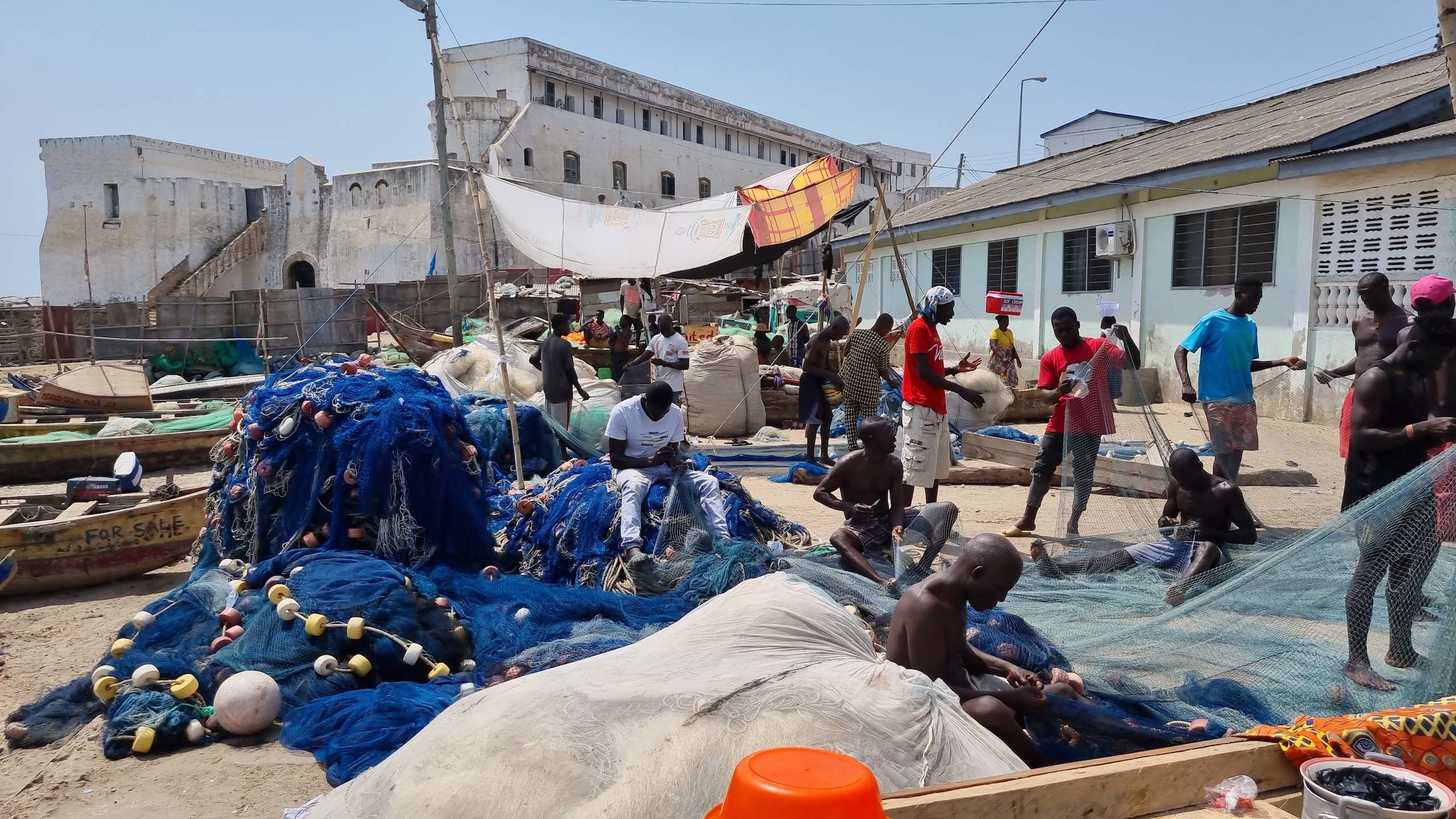 Fishers mend their nets by the seashore in Cape Coast, Ghana.