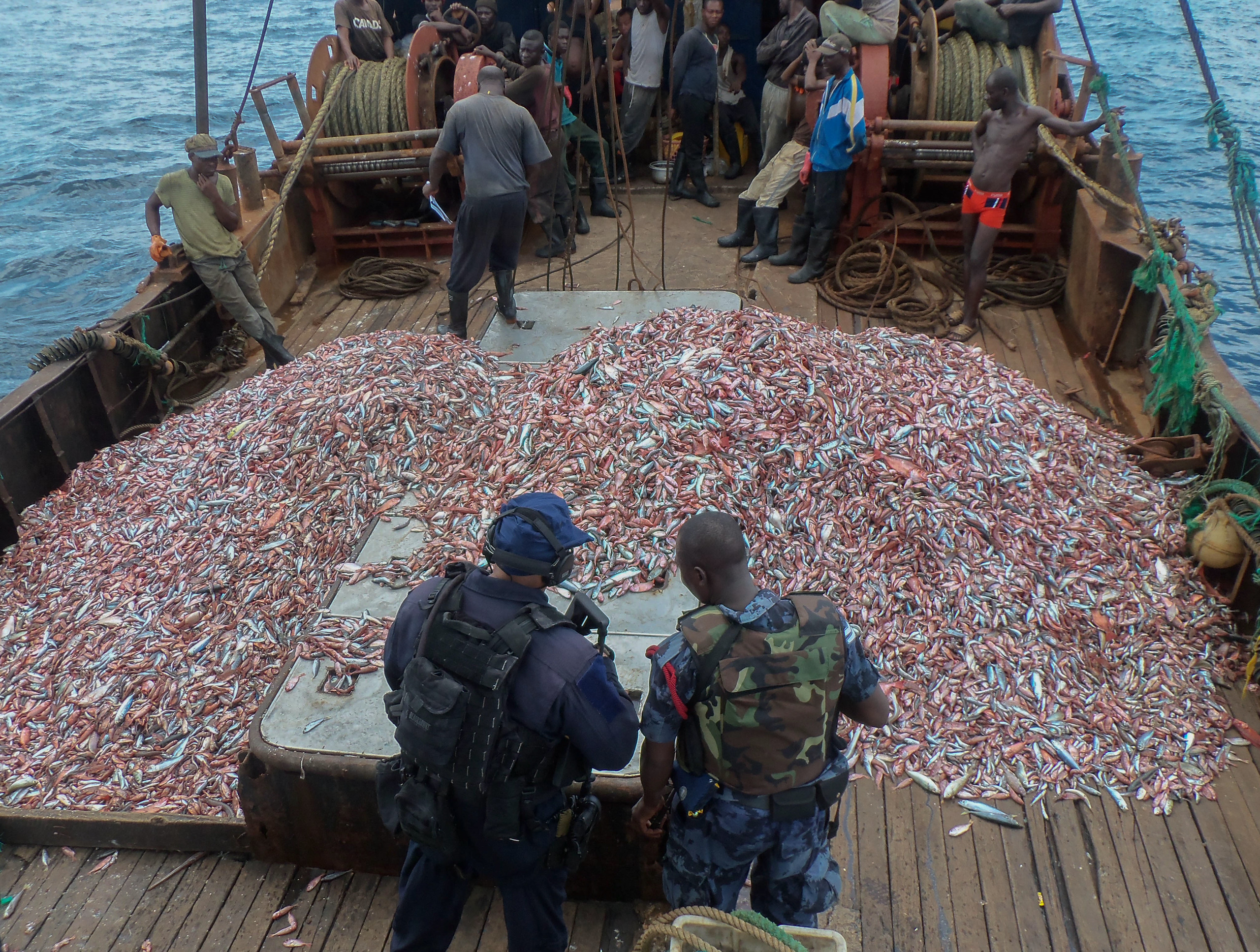 A Ghana Navy officer and US counterpart inspect a vessel suspected of illegal fishing