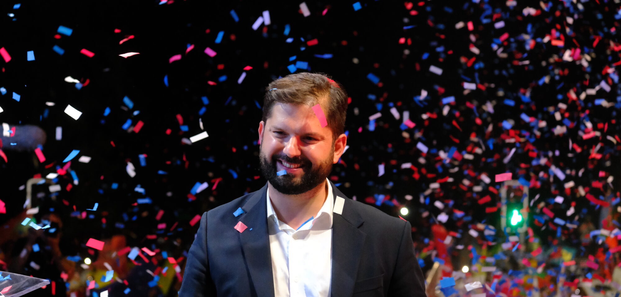 Gabriel Boric smiling amidst red, white and blue papers