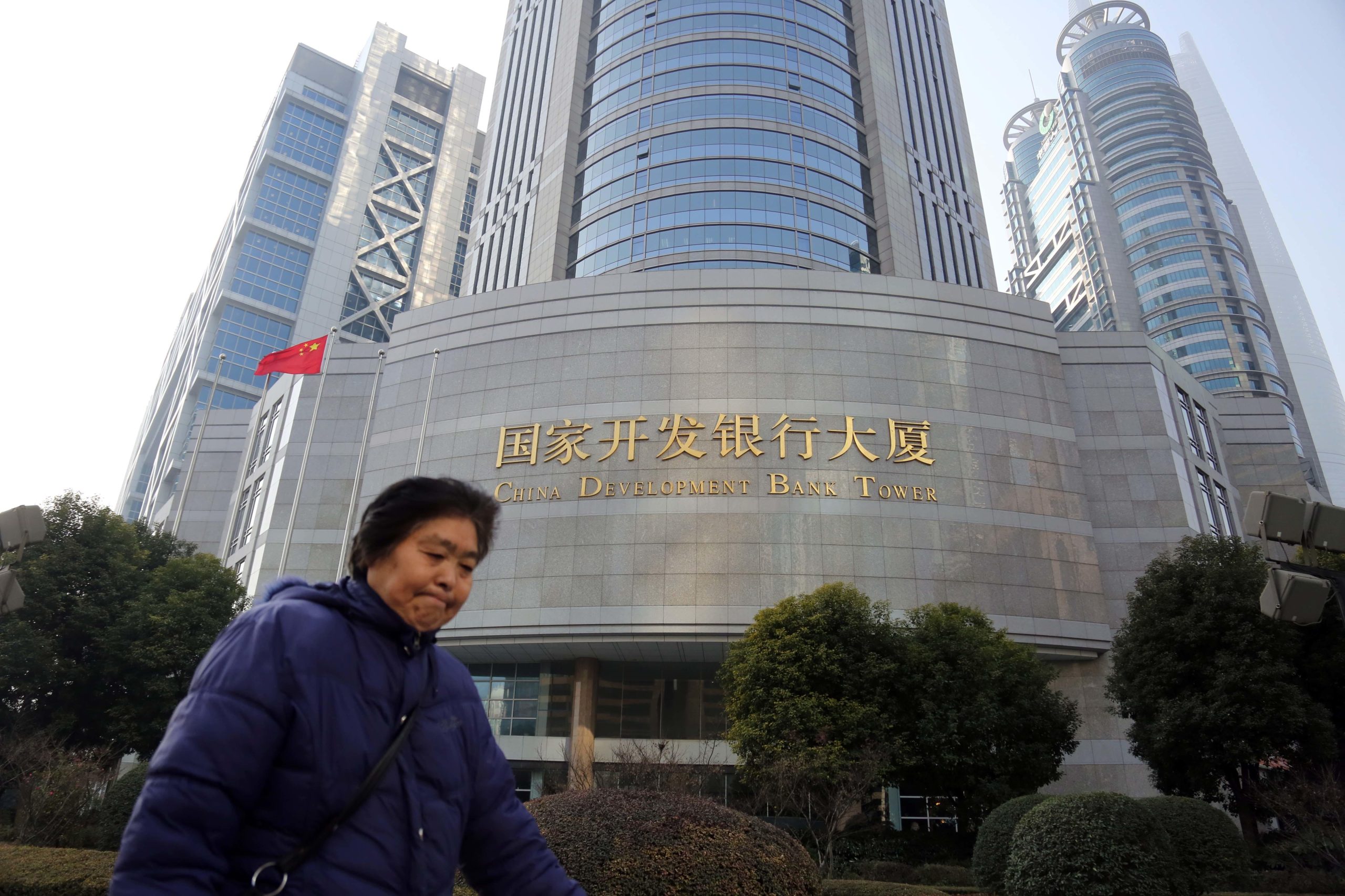 mulher caminha em frente ao prédio do banco chinês de desenvolvimento