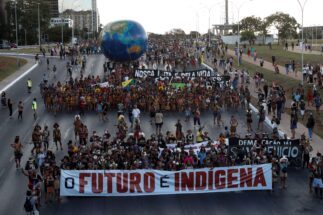<p>Indigenous people protest against Brazilian president Jair Bolsonaro and in favour of the demarcation of indigenous lands, in Brasília, April 2022. The group carries a banner with the words ‘The future is indigenous’ (Image: Adriano Machado / Alamy)</p>