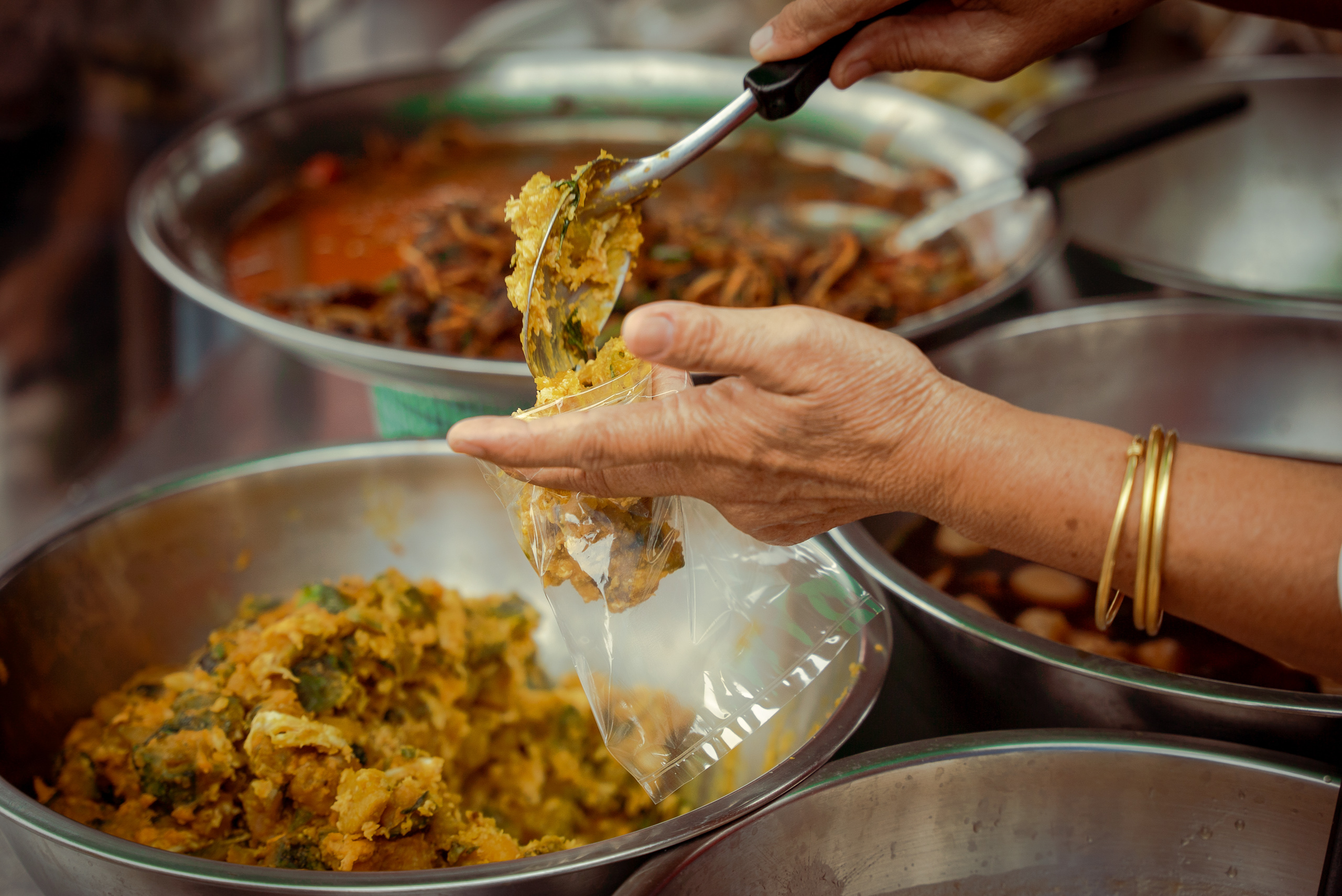 hand dishing food into clear plastic bag