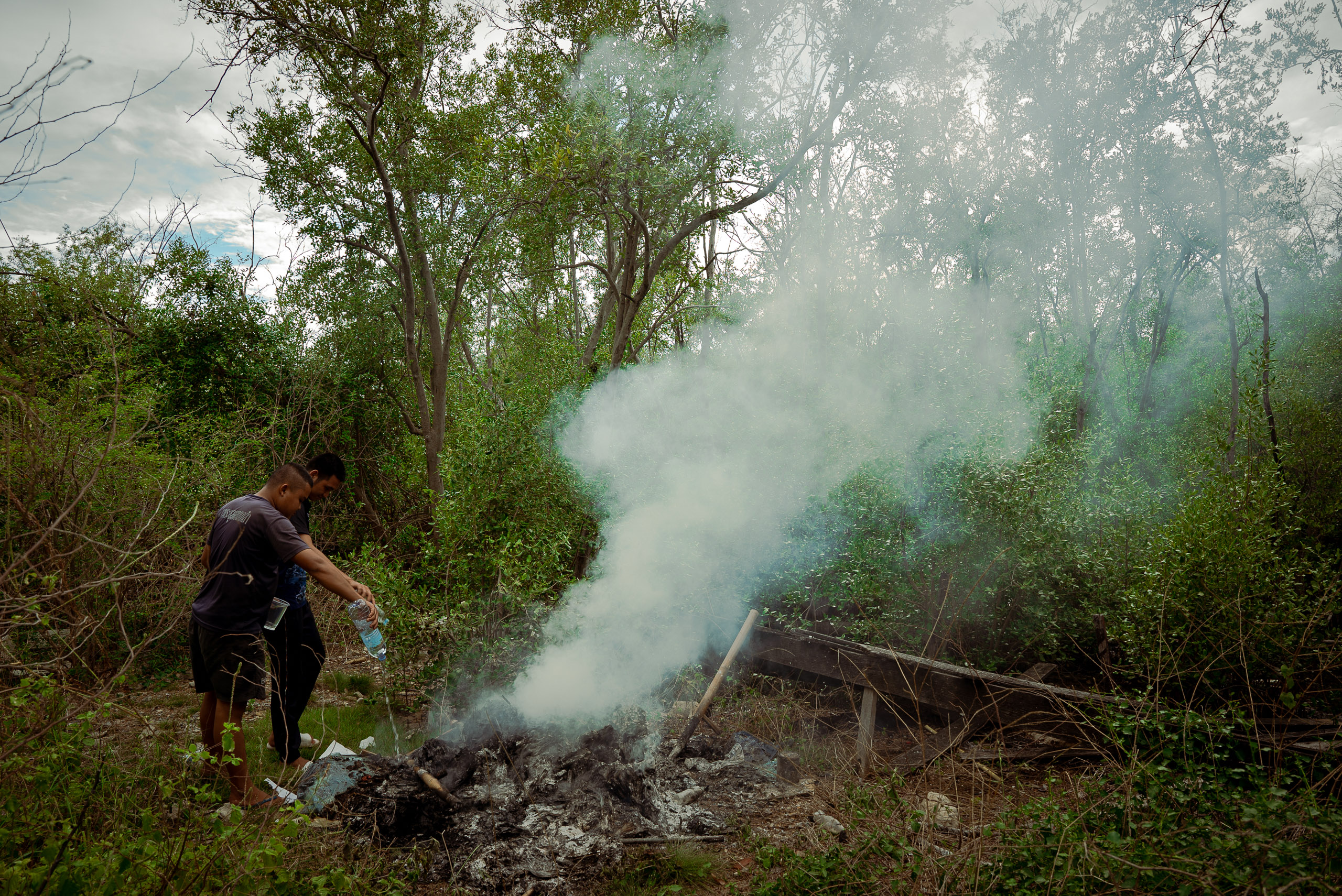 people pouring fluid onto burning waste