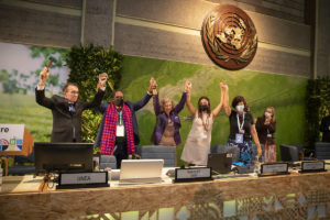 UN Environment Programme (UNEP) committee members hold hands in celebration of passing a resolution on a global plastics treaty