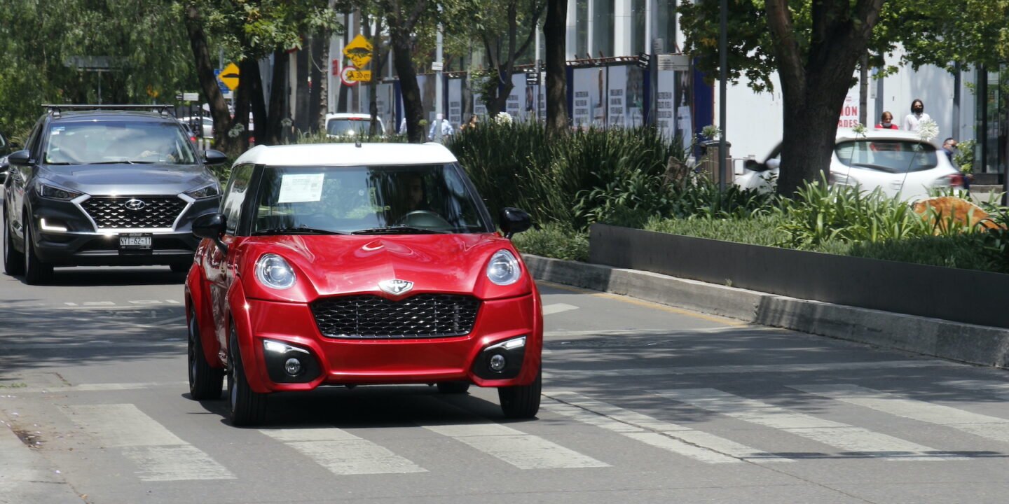 Um carro elétrico vermelho dirigindo em uma rua