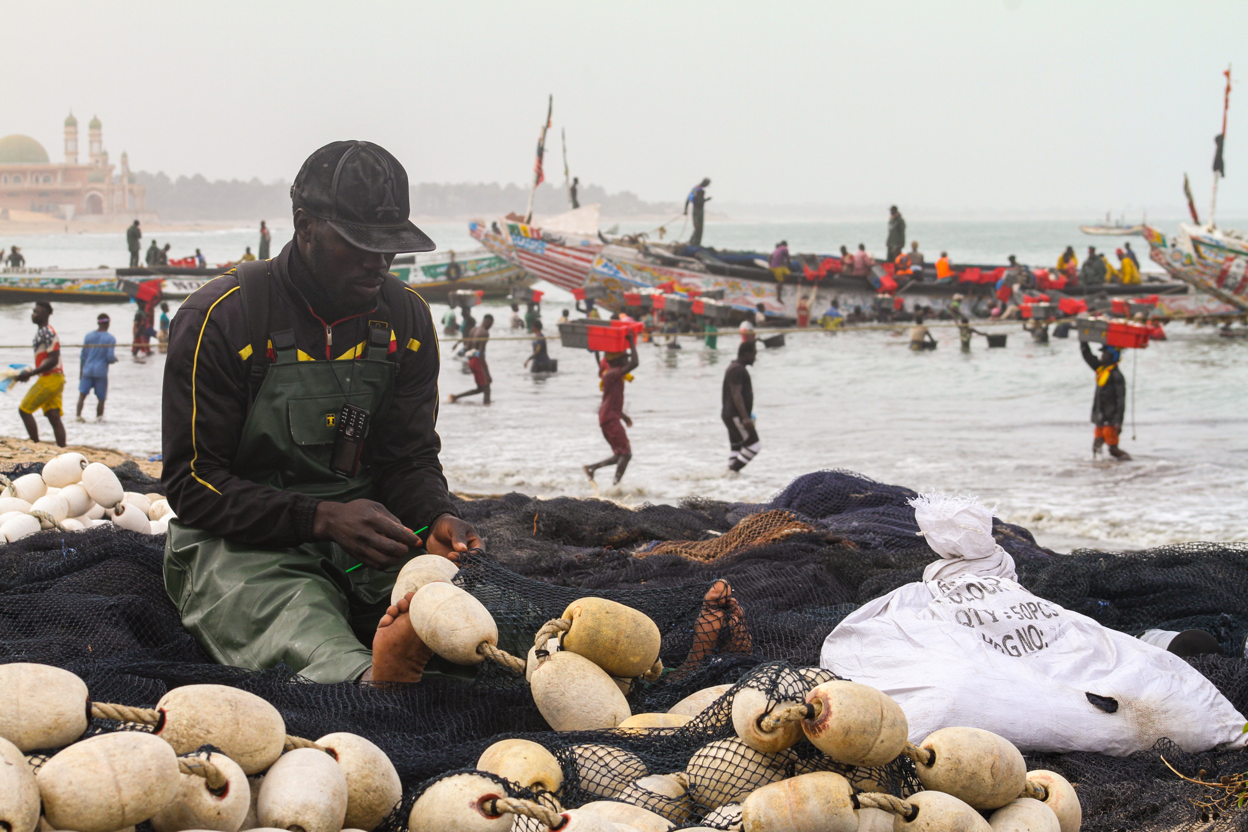 man sitting on and mending fishing net