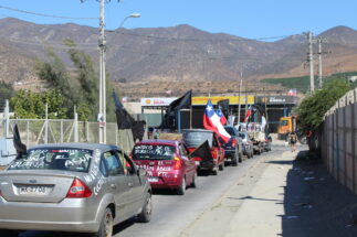 row of cars with anti-mining inscriptions and chilean flags