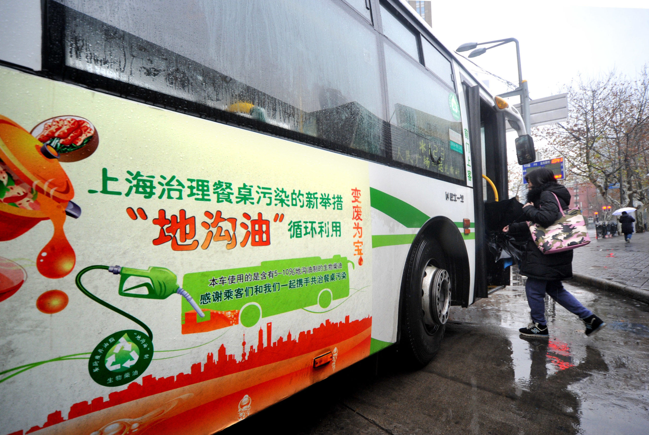 passenger boards a bus on a rainy day