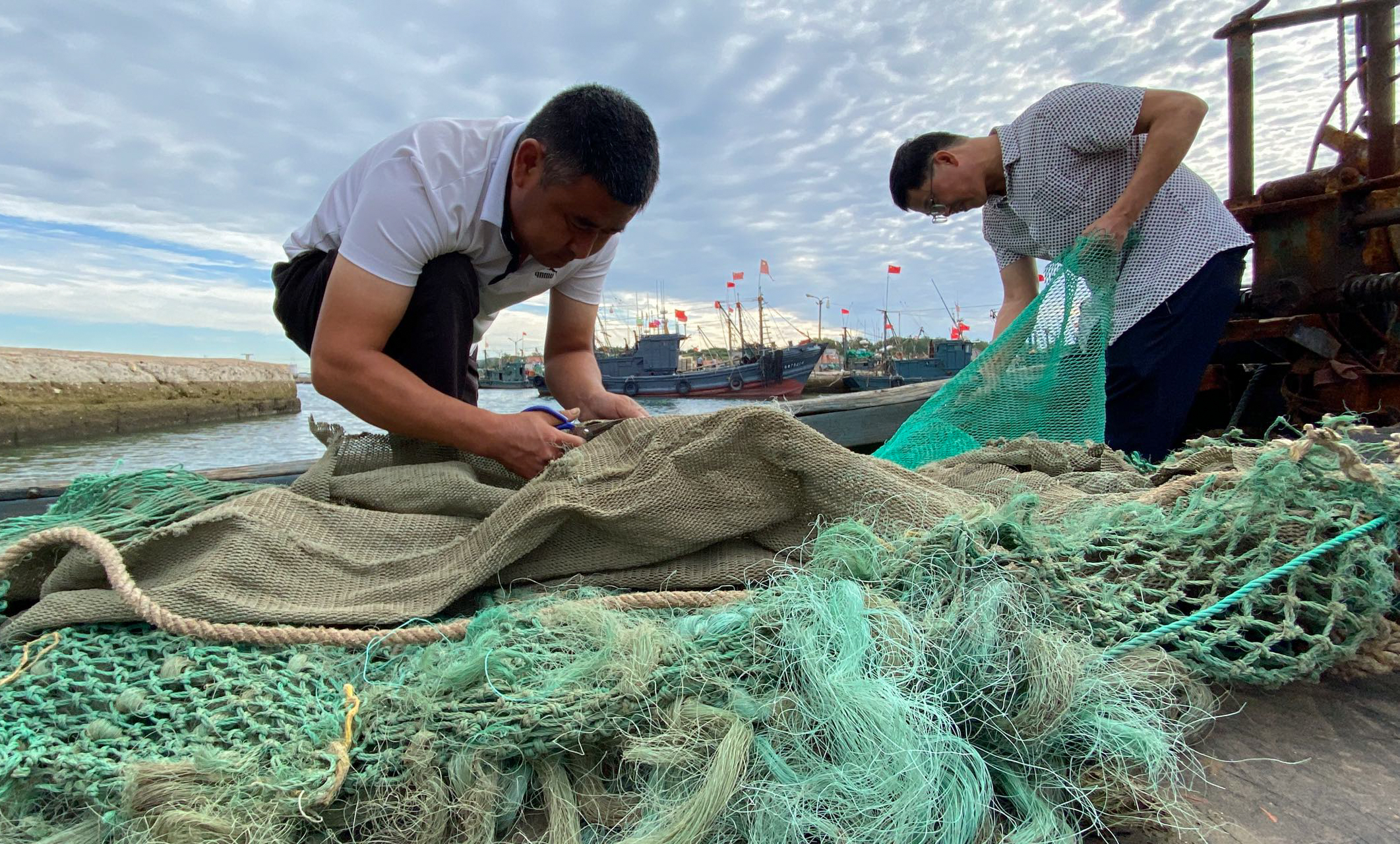 Fishers repair nets in preparation for taking sample catches 