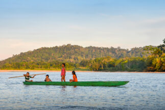 quatro crianças em uma canoa verde no rio Napo