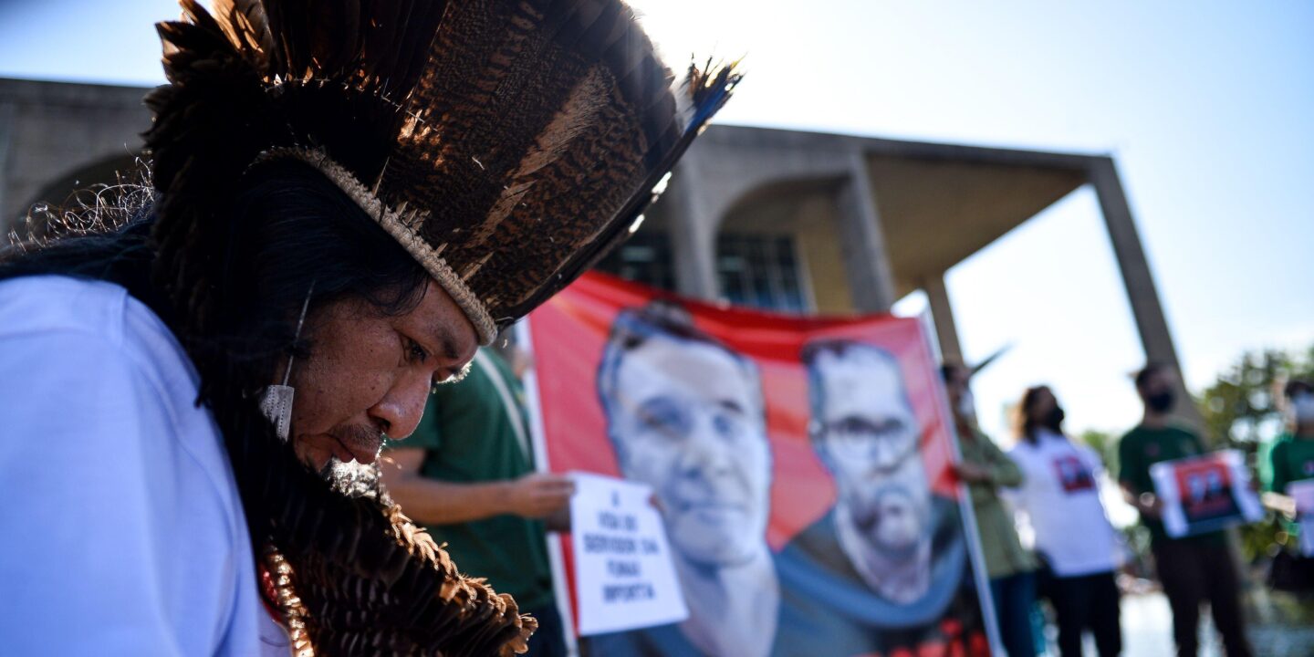 <p>Manifestante indígena protesta em frente ao Ministério da Justiça em junho, após o desaparecimento de Dom Phillips e Bruno Pereira na Amazônia. Seus assassinatos chamaram a atenção mundial para os perigos que ativistas ambientais enfrentam na região (Imagem: Antonio Molina / Foto Arena / Alamy)</p>