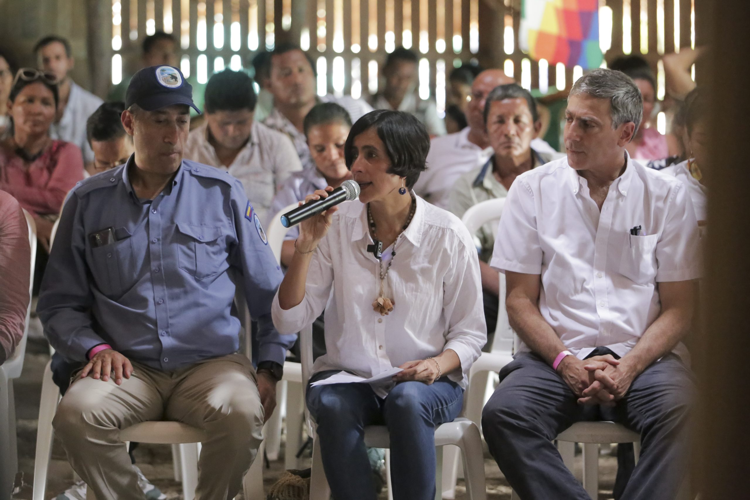 Susana Muhamad com um microfone na mão, sentada em meio a um grupo de pessoas.