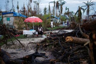 <p>Vendedora trabalha em meio a danos causados pelo furacão Matthew, no Haiti, em outubro de 2016. O financiamento por perdas e danos causados pelas mudanças climáticas tem sido a questão mais controversa da COP27 (Imagem: Carlos Garcia Rawlins / Alamy)</p>