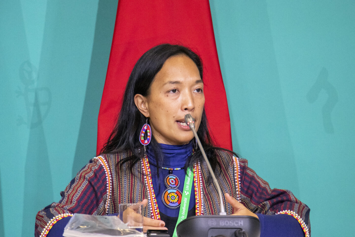 Una mujer con vestimenta tradicional habla frente a un micrófono