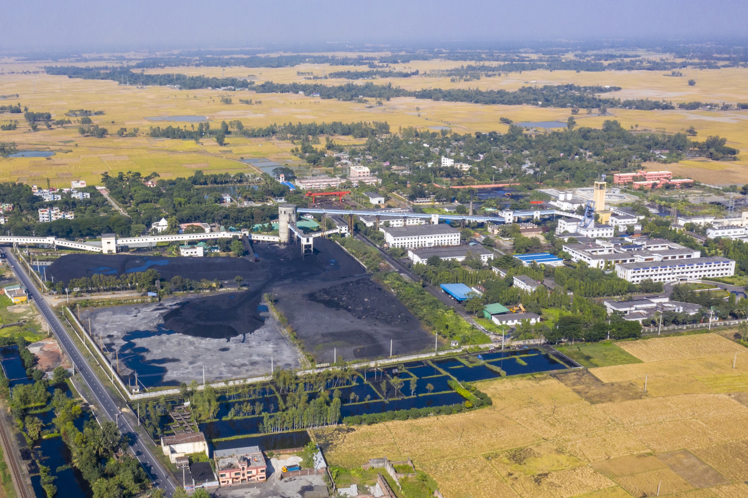 <p>Piles of coal from the underground mine at Barapukuria in northern Bangladesh, pictured in November 2022. The coal is transported via conveyor belt to the adjoining power plant. Untreated black slurry from the mine is released into local water bodies, which are used to irrigate the surrounding fields. (Image: The Third Pole)</p>