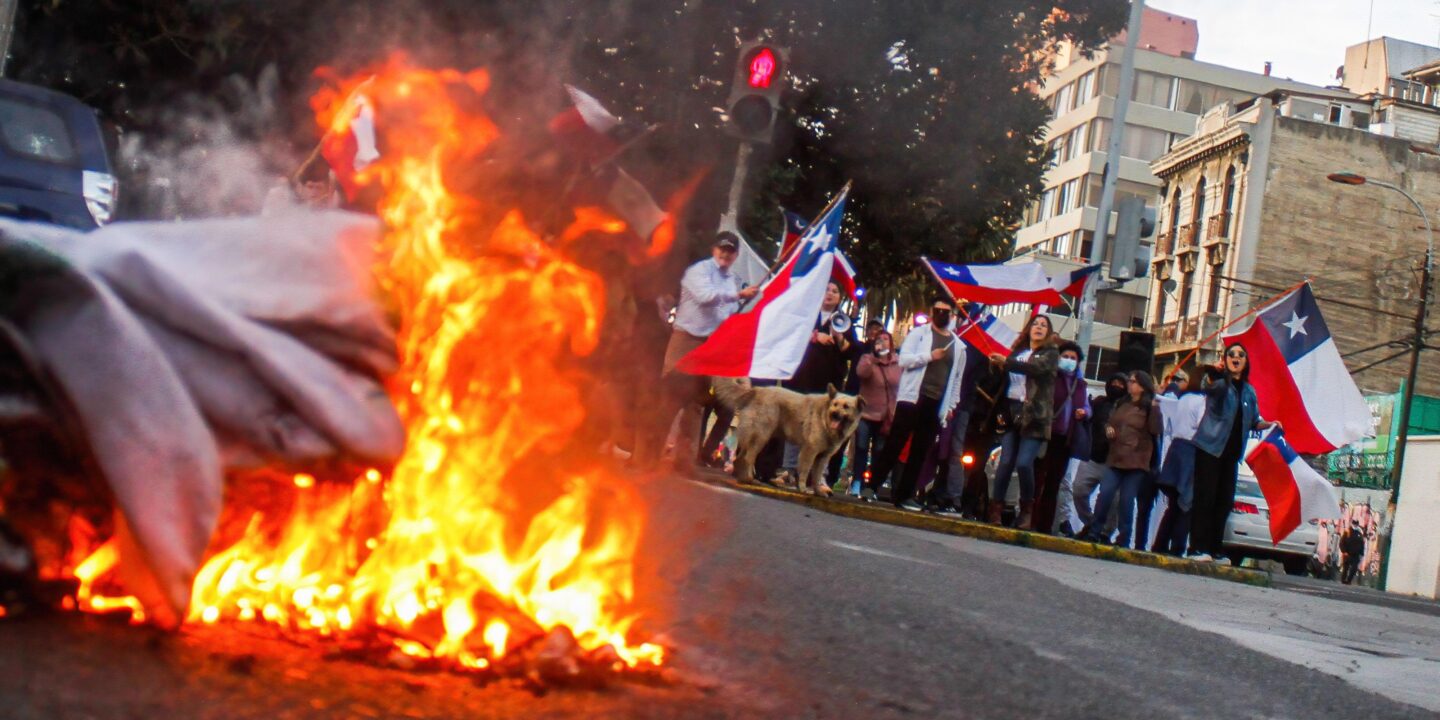 <p>Faixa de apoio à nova Constituição do Chile é queimada em protesto da campanha do &#8220;rechazo&#8221; em Valparaíso, em agosto de 2022. Os chilenos votaram pela rejeição da reforma constitucional em um referendo em setembro (Imagem: Cristobal Basaure Araya / SIPA / Alamy)</p>