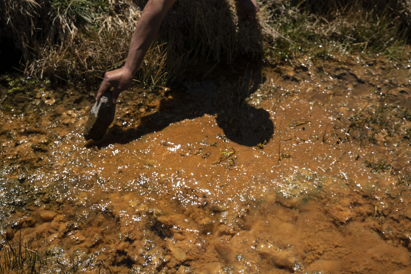 Uma pessoa mostra uma fonte de água contaminada no corredor de mineração do Peru