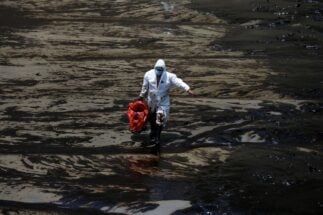 A worker walks on a beach at Ventanilla Peru on 18 January 2022 following oil spill
