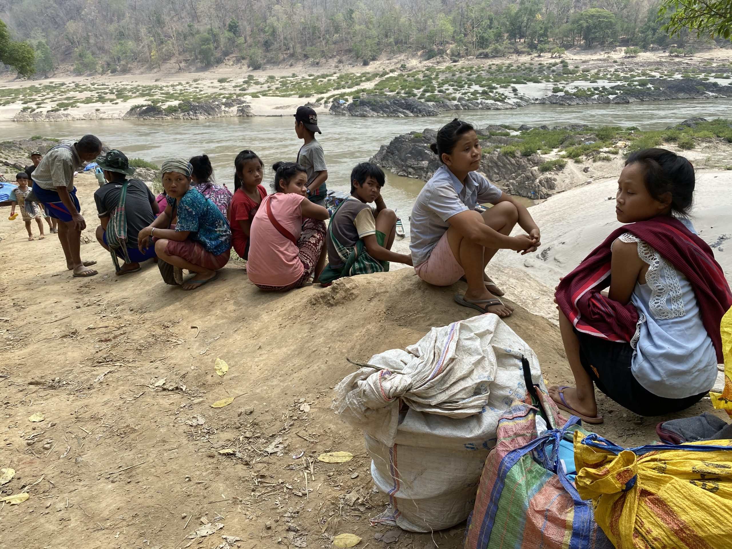 people sitting on rocks near riverbank