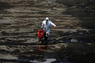Trabalhador limpa praia em Ventanilla, no Peru, três dias após o vazamento de milhares de barris de petróleo de uma refinaria da empresa espanhola Repsol, em janeiro de 2022 (Imagem: Pilar Olivares / Alamy)