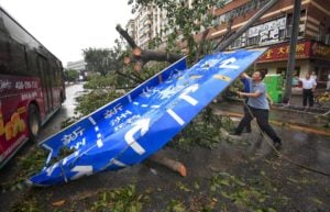 eople clear a fallen guideboard after typhoon in Shenzhen, Guangdong