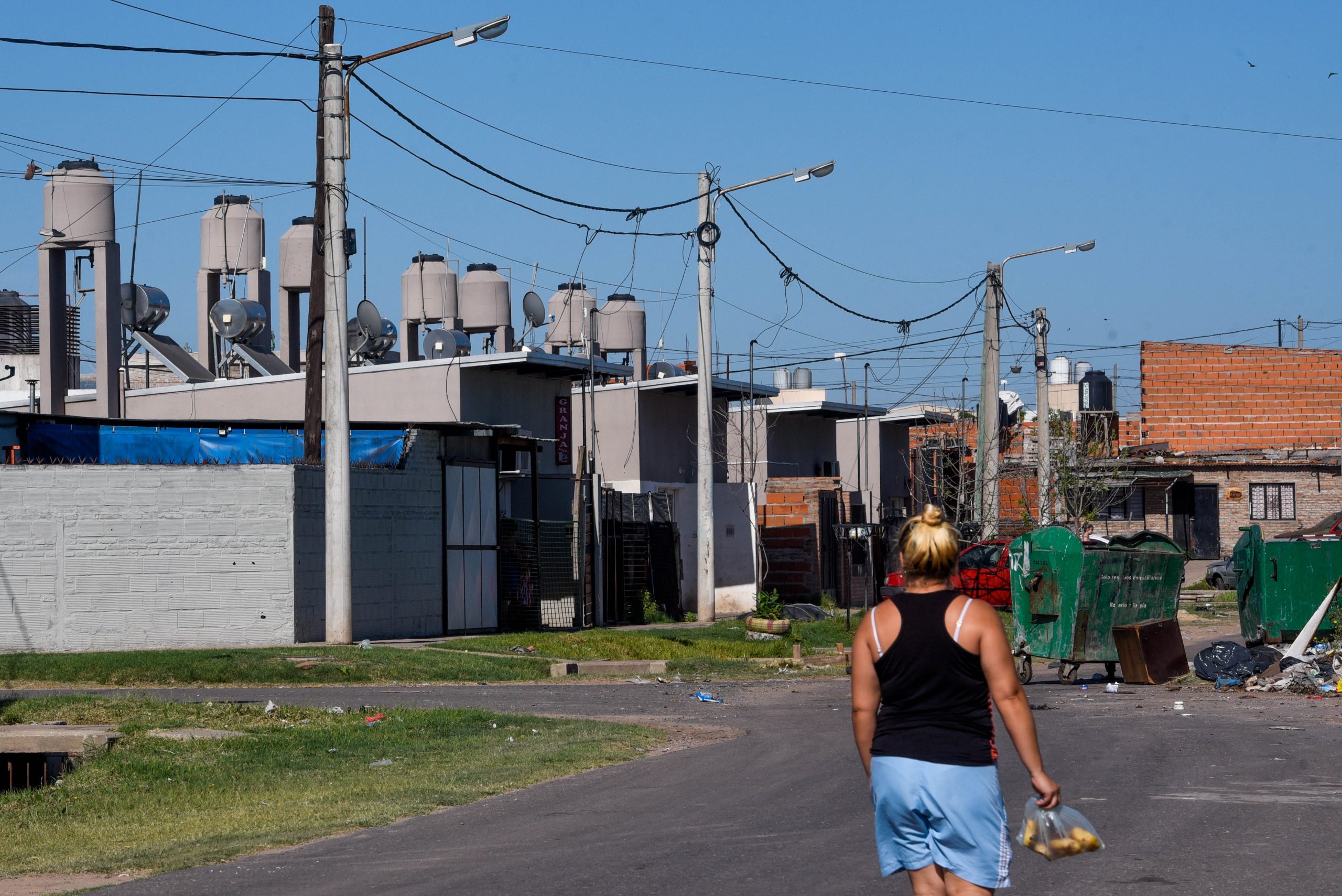 Mulher caminha pelo bairro Godoy, em Rosario, na Argentina. No fundo, casas com aquecedores solares no teto.