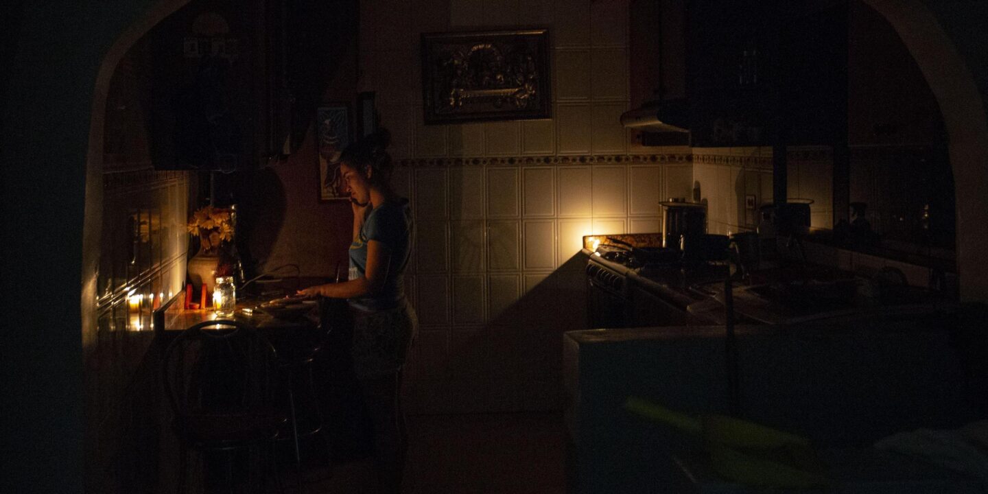 <p>Mulher cozinha à luz de velas em Caracas, na Venezuela, durante apagão em 2020 (Imagem: Luis Morillo / Alamy)</p>
