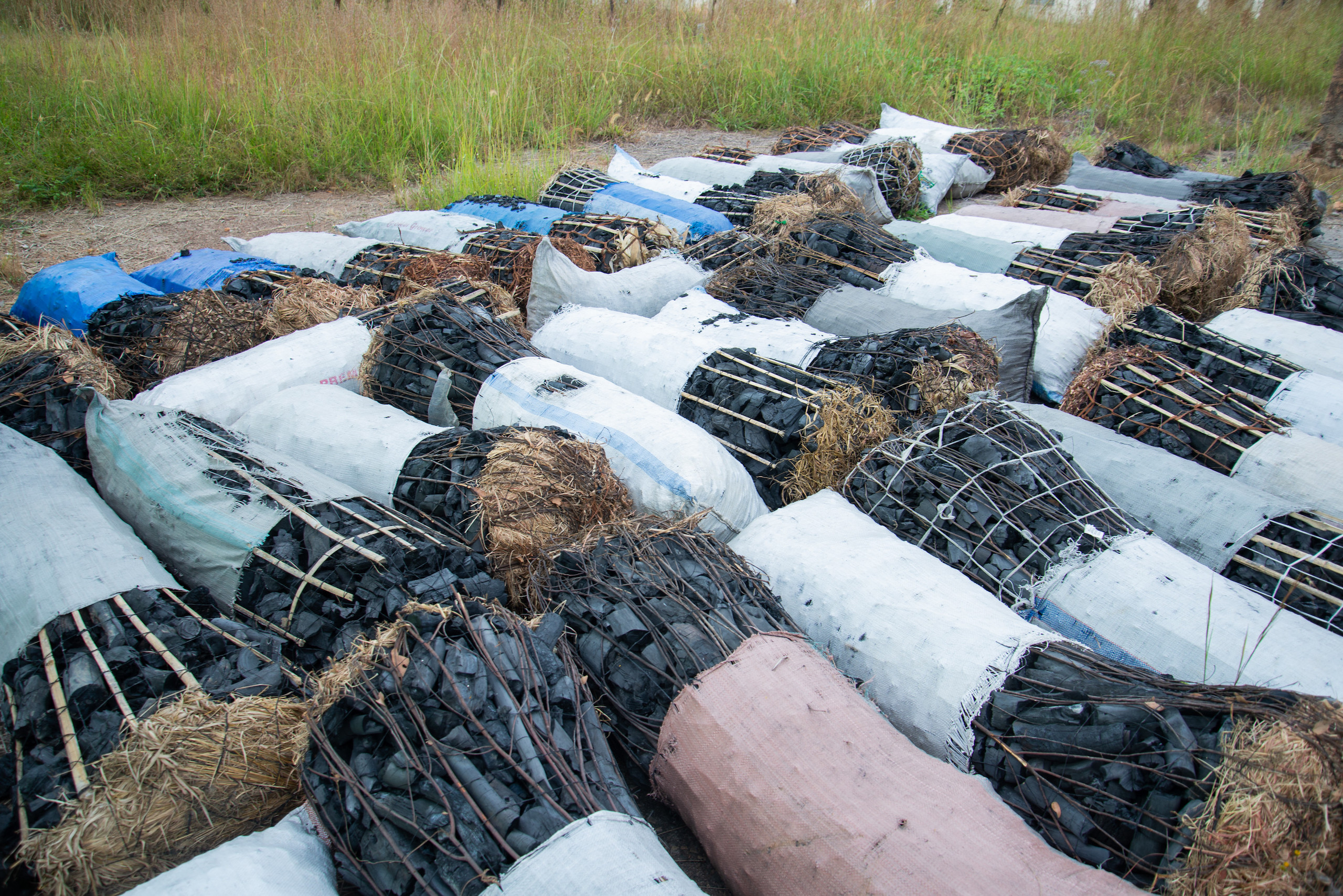 Bundles of charcoal wrapped in mesh laid on the ground. The miombo forests in the north of the country are heavily degraded, in part due to over-harvesting for charcoal production