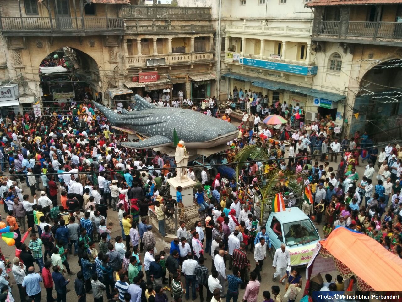 a life-sized inflatable model of a whale shark in the middle of a crowd of people, town square Gujarat, India