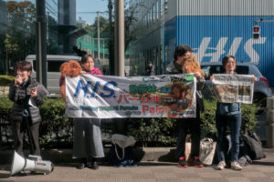 Four protestors hold signs calling for a stop to a proposed palm oil power plant, due to be built in Japan’s Miyagi prefecture by HIS Super Power, a subsidiary of a major travel company