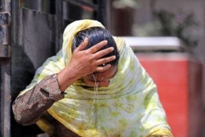 A woman washing her face with water at a roadside water pipeline during high temperatures in Dhaka, Bangladesh, April 11 2023