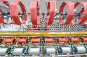 Woman behind machines pulling thread