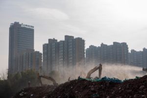 Demolition site, diggers silhouetted against cityscape, skyscrapers in Jiangsu province, construction and demolition in China