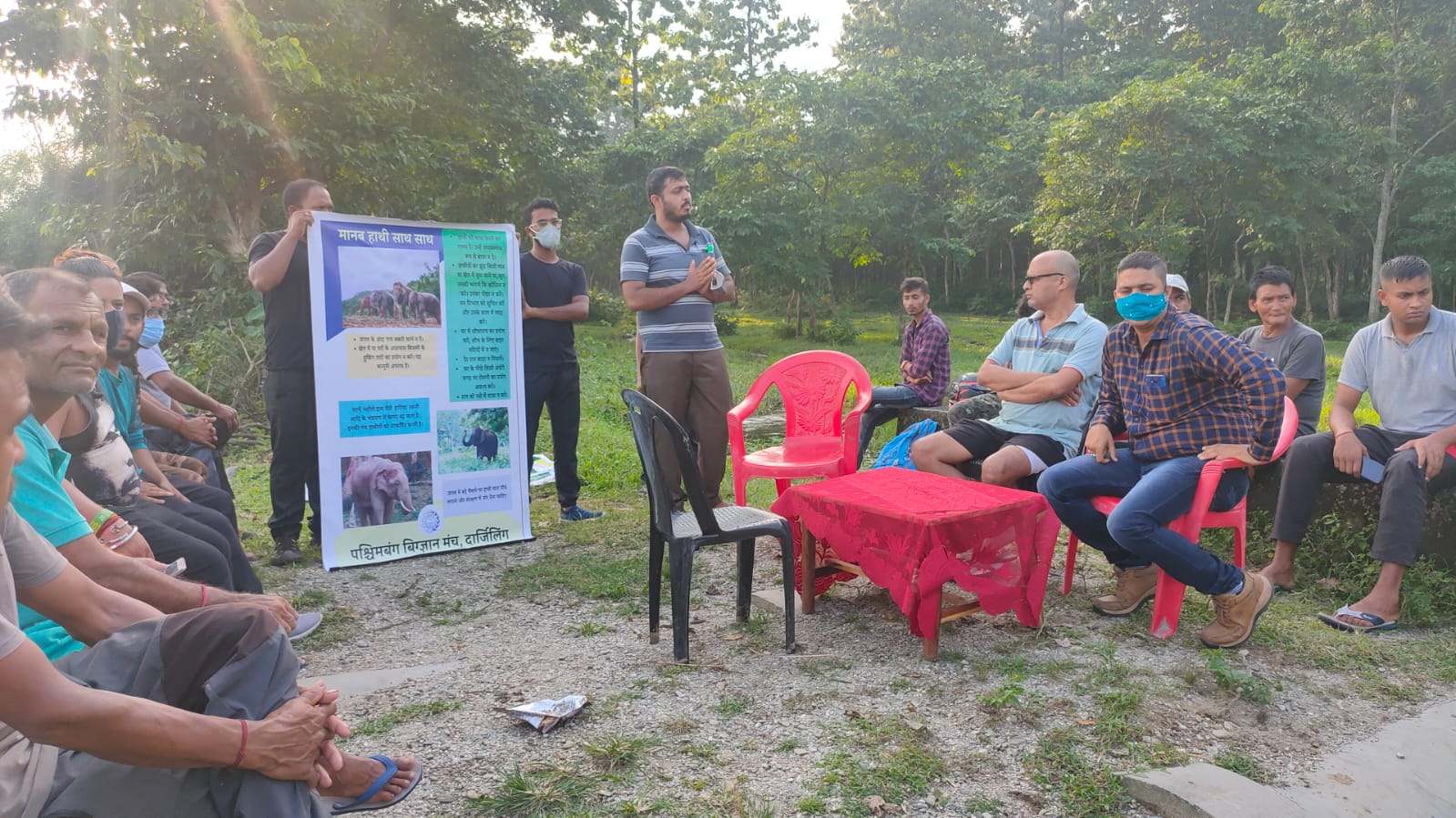 people giving presentation to group of people seated outside