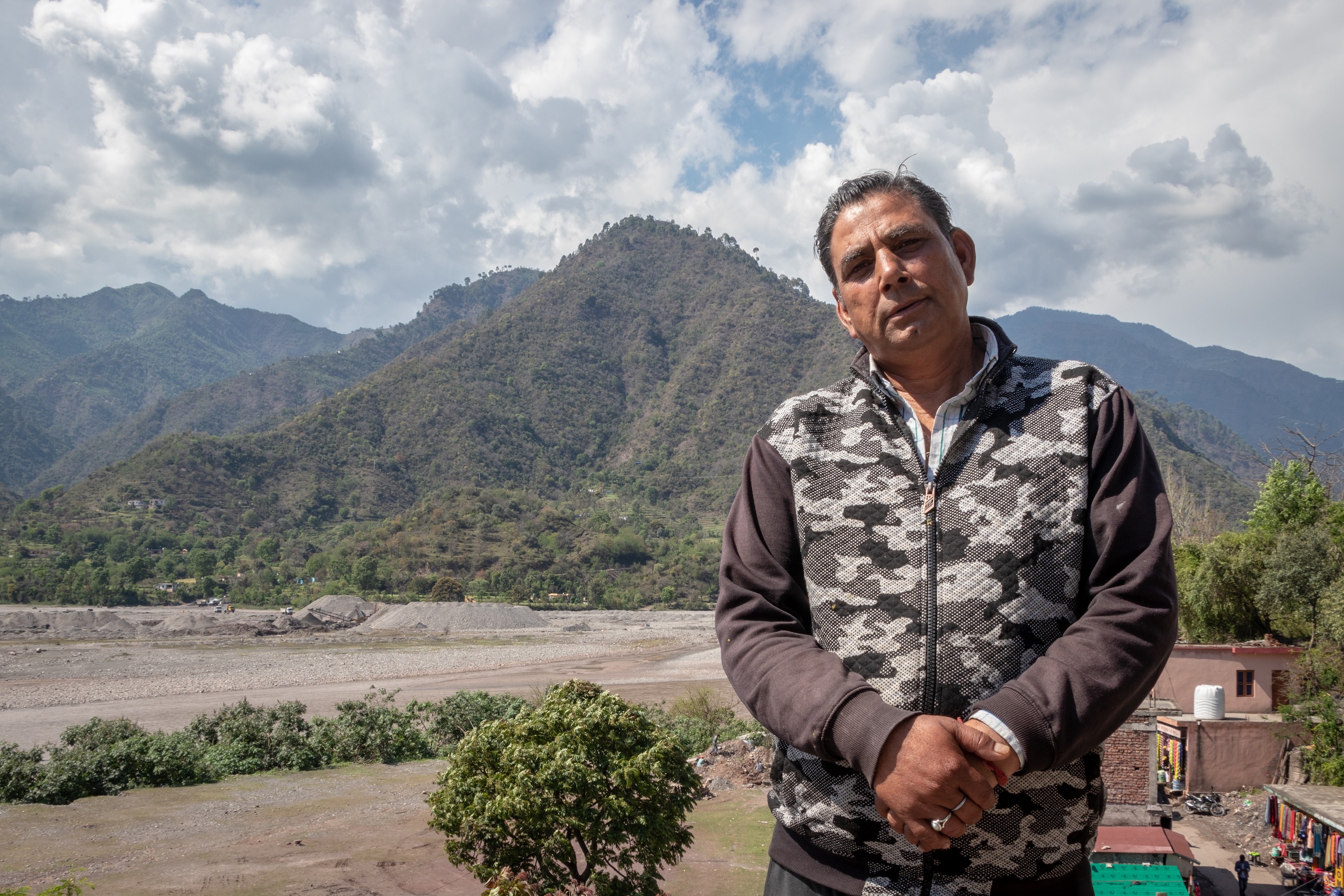 Sunil Abrol, 55, an electronics store owner from Arnas in Reasi district, Jammu and Kashmir stands past the Chenab river in Arnas where maximum sand mining activity takes place.  (Image : Ashish Kumar Kataria)