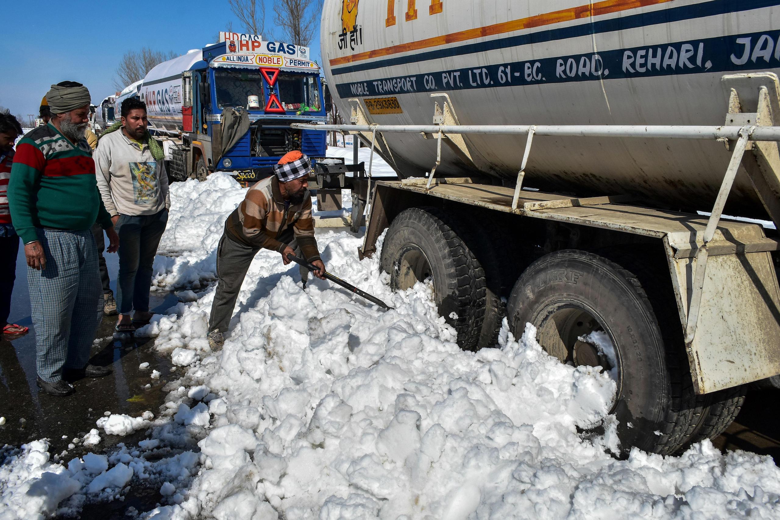 A stranded driver seen clearing snow around his truck on a closed National Highway in Qazigund, about 85kms from Srinagar, Indian administered Kashmir.  The main National Highway that connects the valley with the rest of country remained closed on Saturday for the fourth consecutive day following an avalanche killing seven people