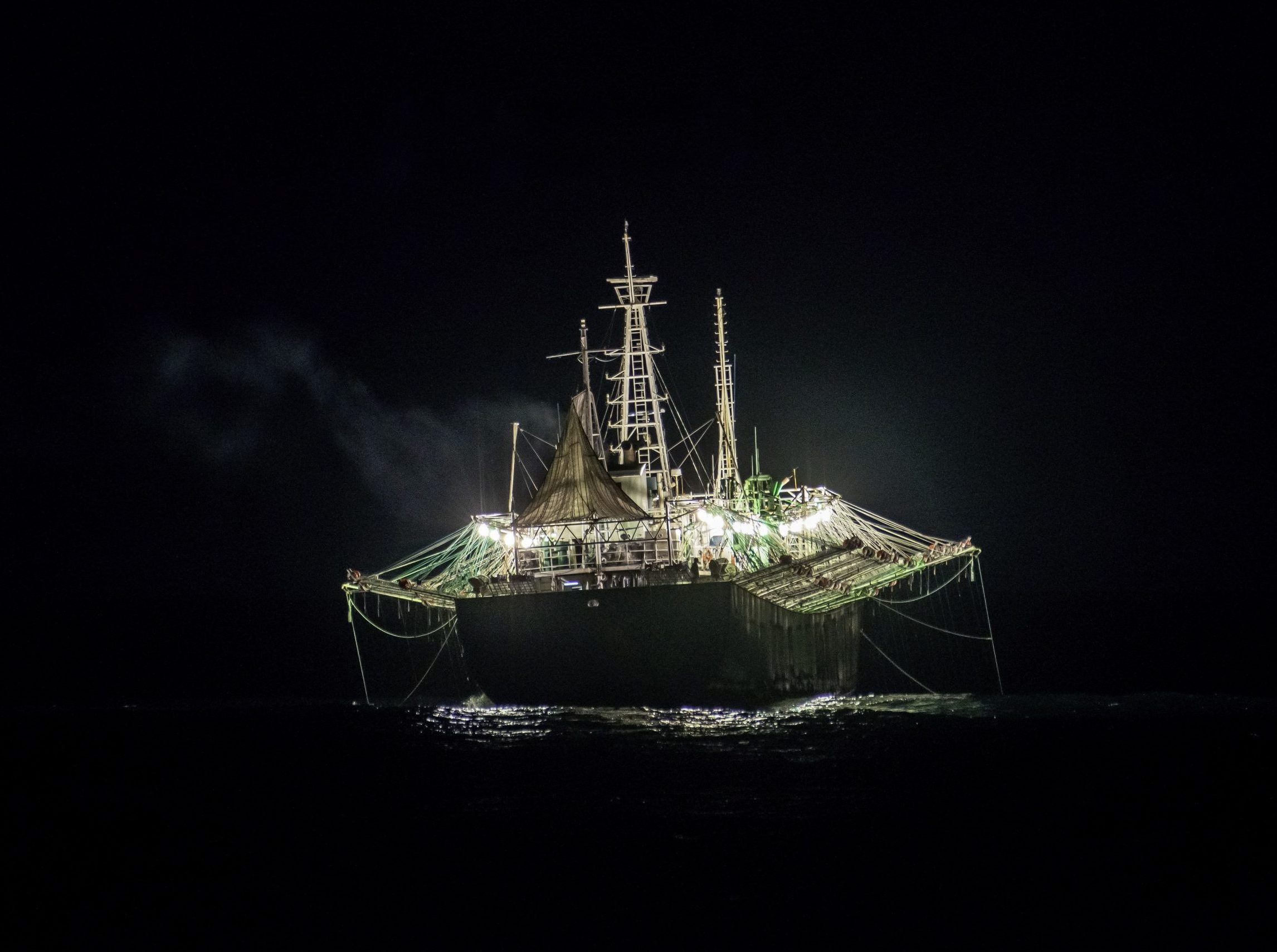ship with lights on dark ocean at night