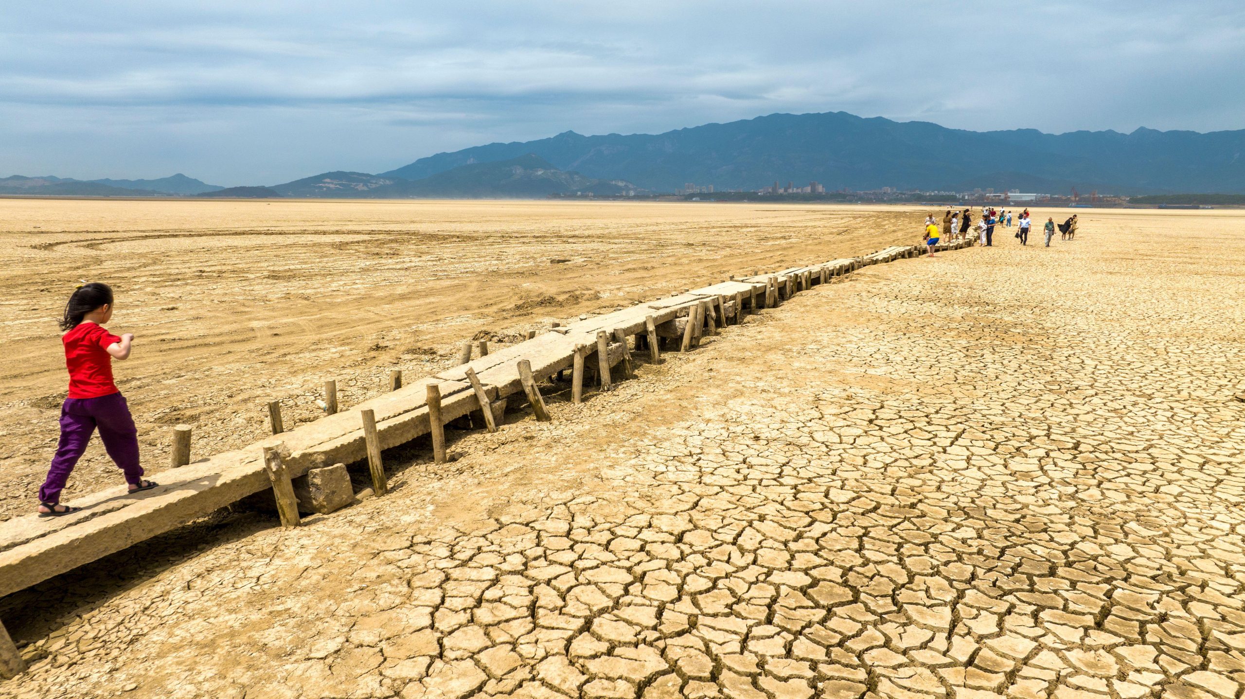 child walking on low bridge over exposed dry lakebed