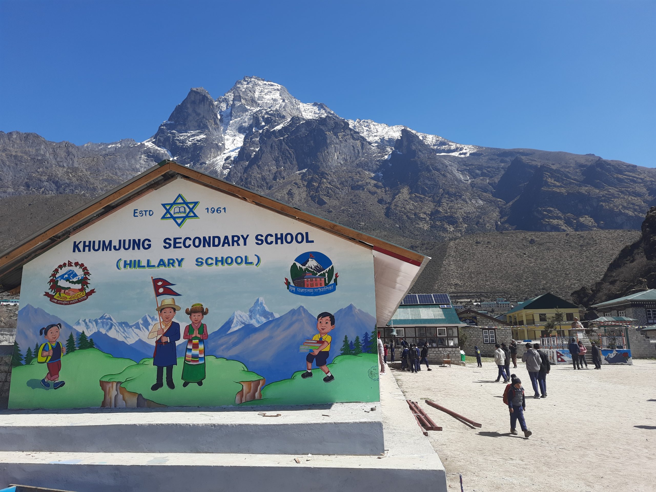 people near school building in front of mountain