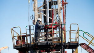 Man operating oil drilling machinery, blue sky background