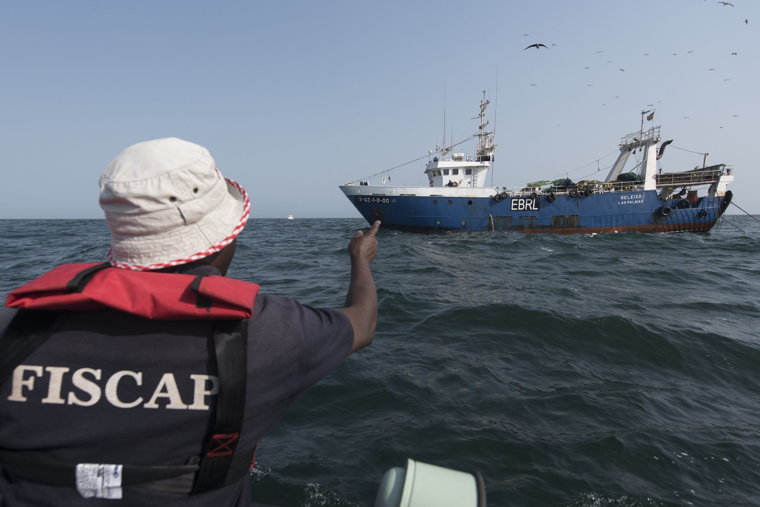 man on boat pointing at ship