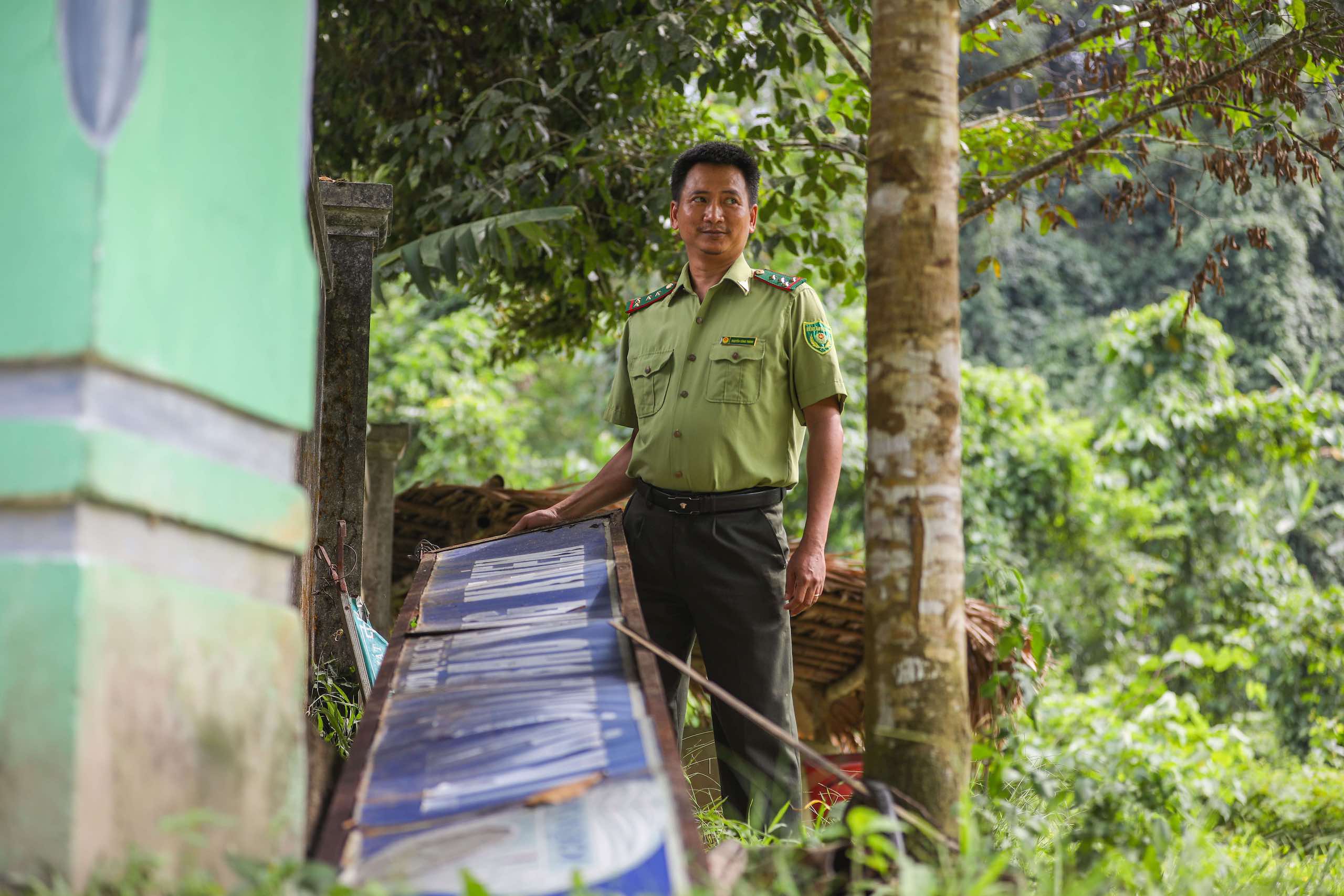 Park ranger stands in forest next to sign on the ground, Vietnam